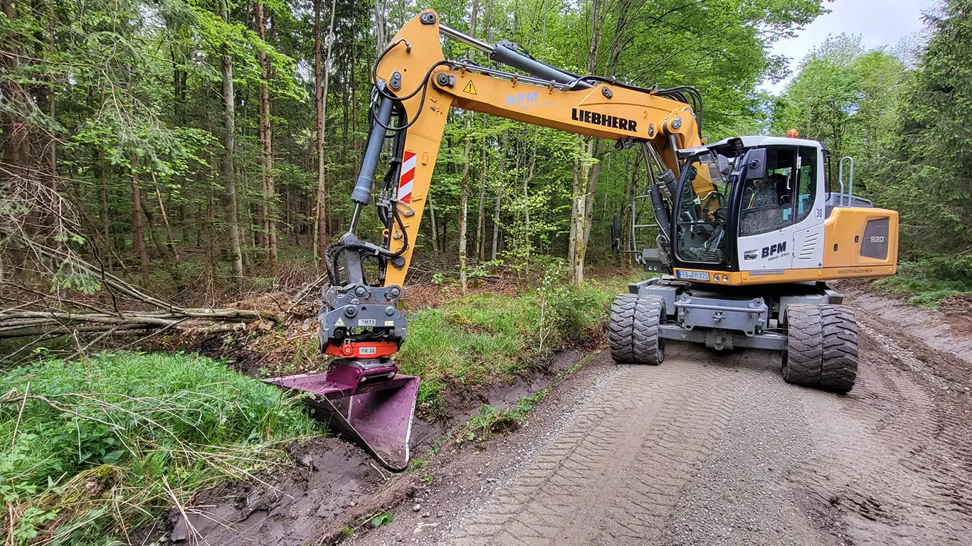 Bagger räumt Graben am Waldweg